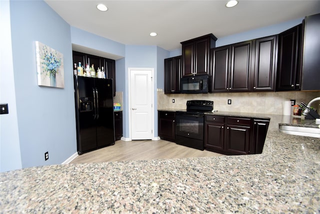 kitchen featuring tasteful backsplash, sink, light stone counters, and black appliances