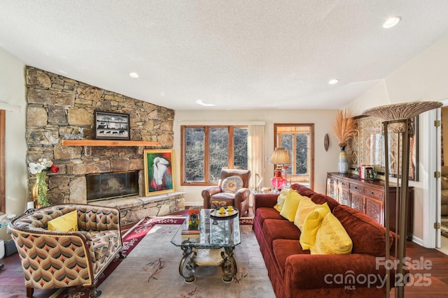 living room with lofted ceiling, wood finished floors, a textured ceiling, a stone fireplace, and recessed lighting