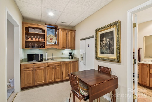 bar with visible vents, a sink, white fridge with ice dispenser, black microwave, and a drop ceiling