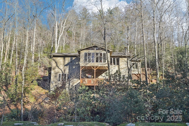 exterior space featuring a view of trees and a wooden deck