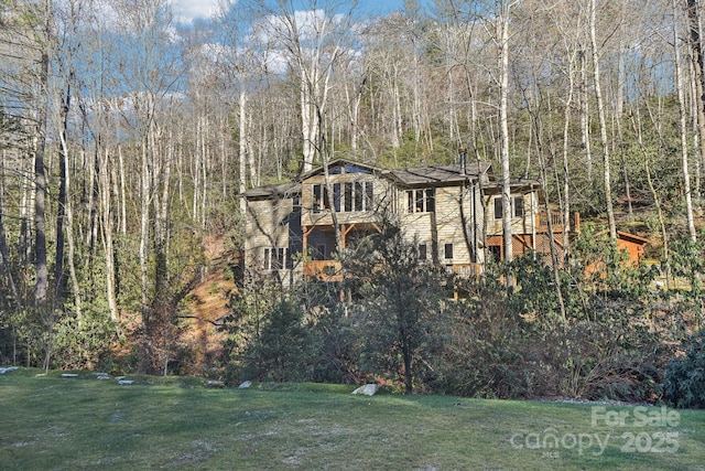 view of front of home featuring a front yard and a view of trees