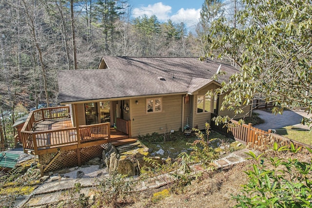 rustic home featuring a shingled roof and a wooden deck