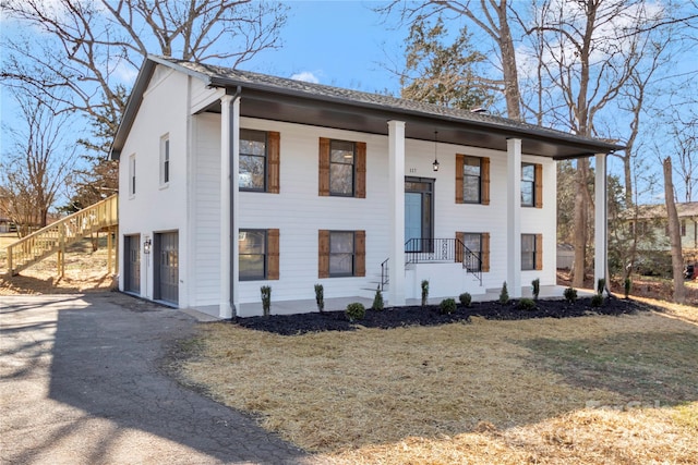 split foyer home with a garage, a front yard, and covered porch