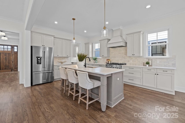 kitchen with premium range hood, dark wood-style flooring, high end fridge, a sink, and stove