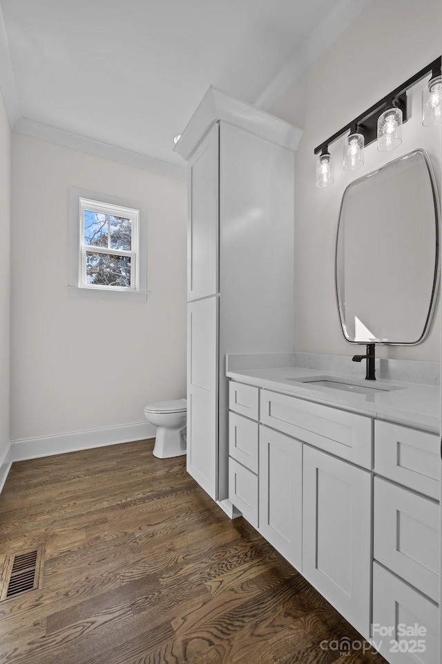 bathroom featuring visible vents, crown molding, toilet, wood finished floors, and vanity