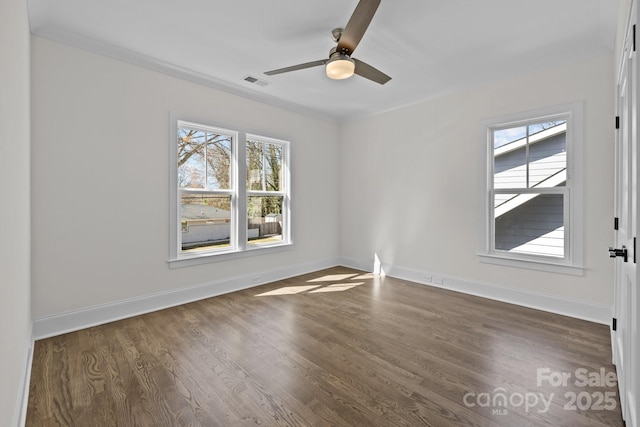 spare room featuring dark wood-type flooring, plenty of natural light, baseboards, and visible vents