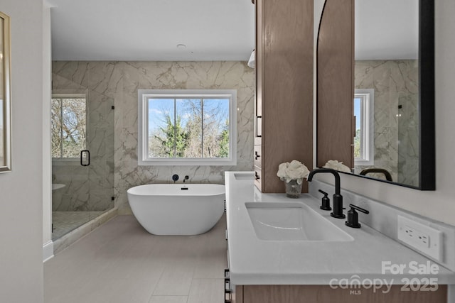 full bathroom featuring vanity, tile walls, a marble finish shower, and a freestanding bath