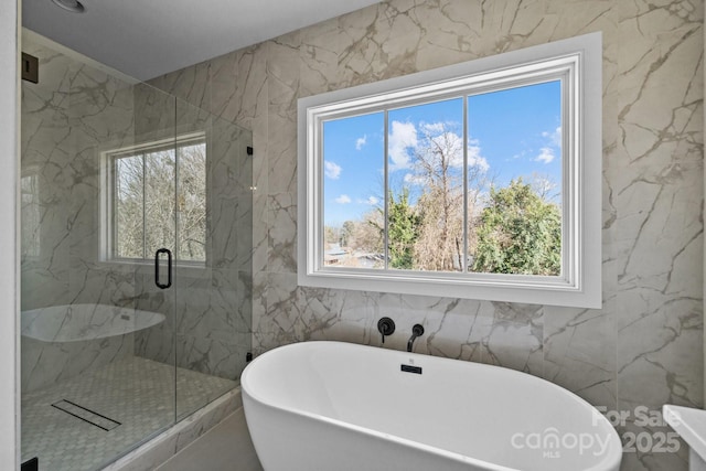 bathroom with a marble finish shower, a soaking tub, and a healthy amount of sunlight