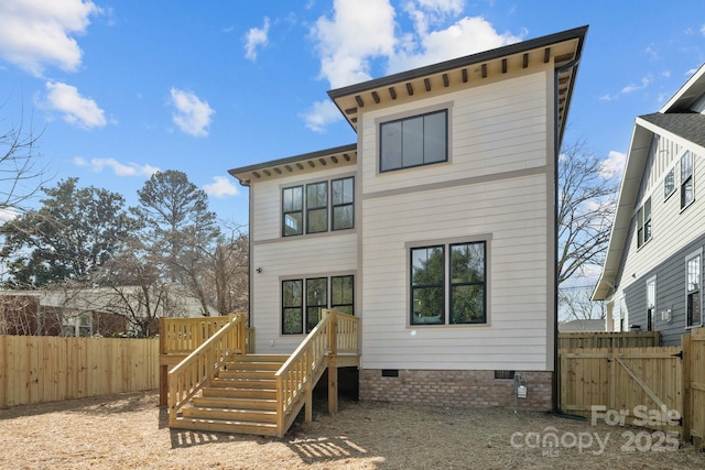 rear view of house featuring crawl space, a deck, and fence