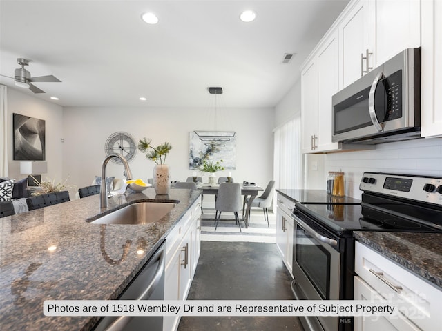 kitchen with sink, dark stone counters, white cabinets, and appliances with stainless steel finishes