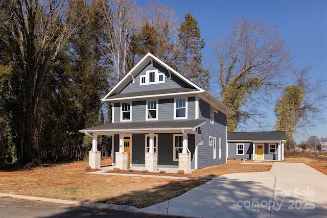 view of front of house featuring a porch, concrete driveway, and roof with shingles