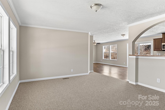 carpeted empty room with crown molding, ceiling fan, and a textured ceiling