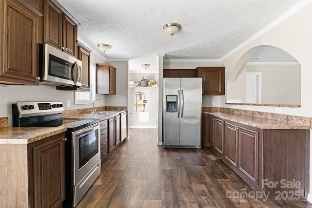 kitchen with dark wood-type flooring, sink, a textured ceiling, ornamental molding, and appliances with stainless steel finishes