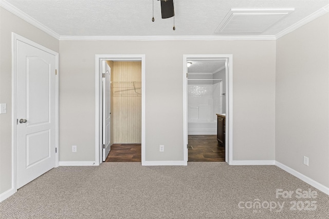 unfurnished bedroom with dark colored carpet, a walk in closet, crown molding, a textured ceiling, and a closet