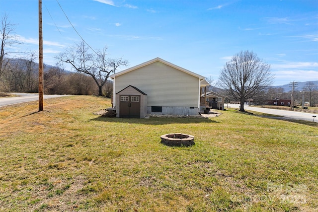 view of home's exterior with a lawn and an outdoor fire pit