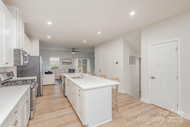 kitchen featuring white cabinetry, sink, a center island with sink, and appliances with stainless steel finishes