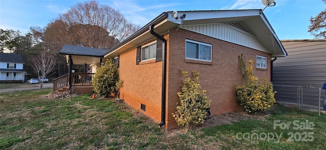 view of side of home featuring brick siding, fence, a lawn, crawl space, and board and batten siding