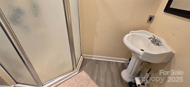 bathroom with a stall shower, baseboards, and wood finished floors