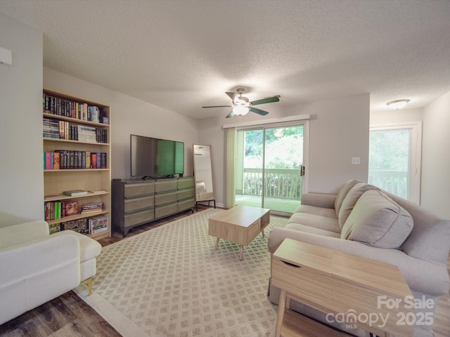 living room with hardwood / wood-style flooring, ceiling fan, and a textured ceiling