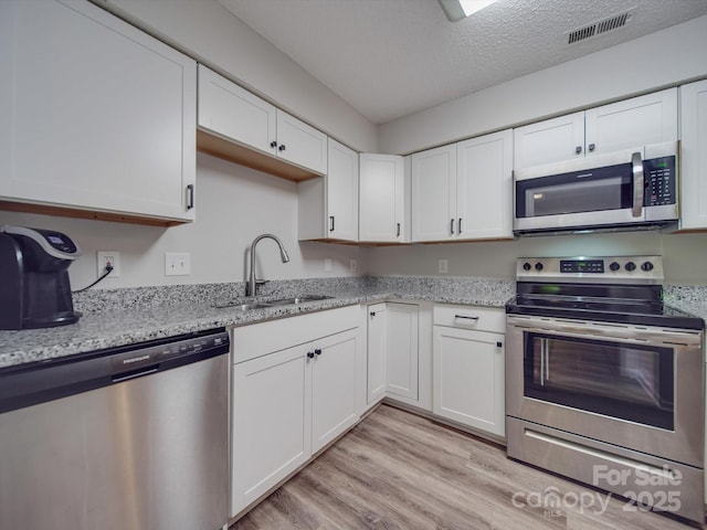 kitchen with appliances with stainless steel finishes, sink, and white cabinets