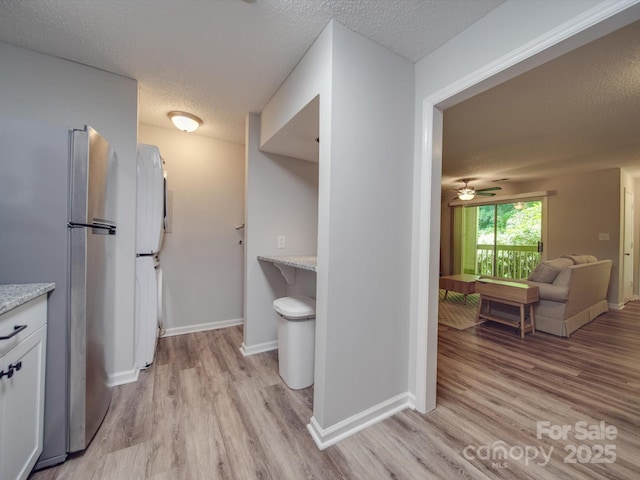 kitchen featuring white cabinetry, light hardwood / wood-style floors, a textured ceiling, and stainless steel refrigerator