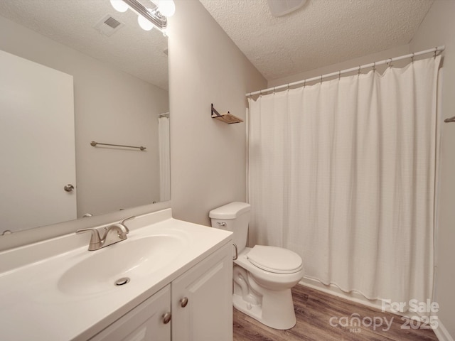 bathroom featuring vanity, hardwood / wood-style flooring, a textured ceiling, and toilet