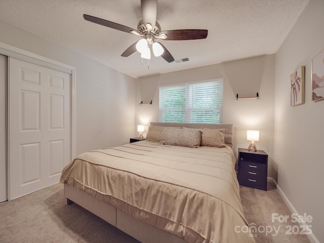 carpeted bedroom with ceiling fan, a closet, and a textured ceiling