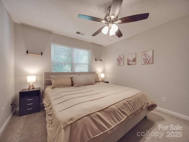 bedroom with ceiling fan, carpet, and a textured ceiling