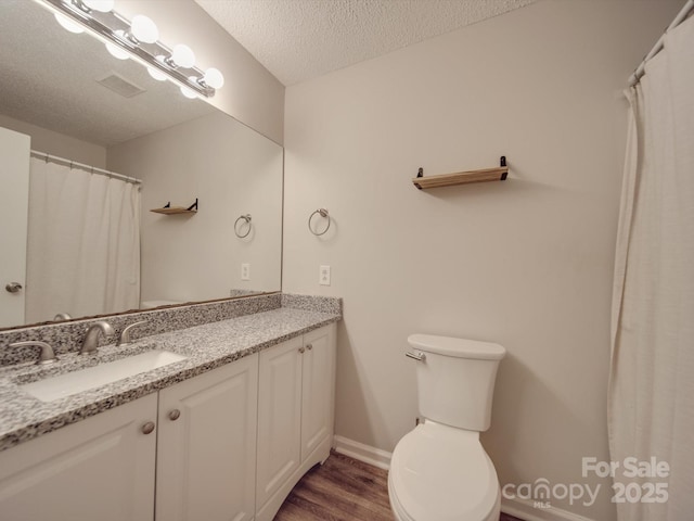 bathroom featuring hardwood / wood-style flooring, vanity, toilet, and a textured ceiling