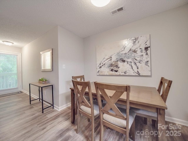 dining room with a textured ceiling and light wood-type flooring