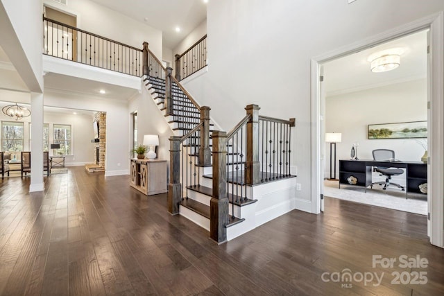 stairway featuring an inviting chandelier, crown molding, a high ceiling, and hardwood / wood-style flooring