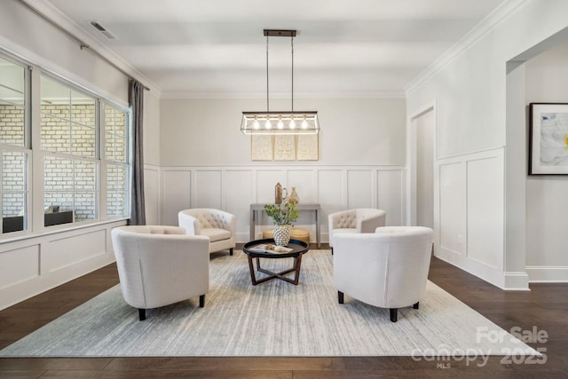 sitting room with ornamental molding, a decorative wall, and wood finished floors