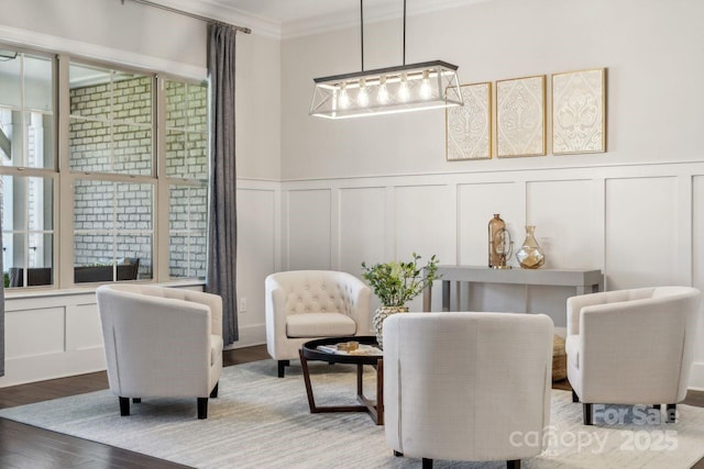 sitting room featuring ornamental molding, wood finished floors, and a decorative wall