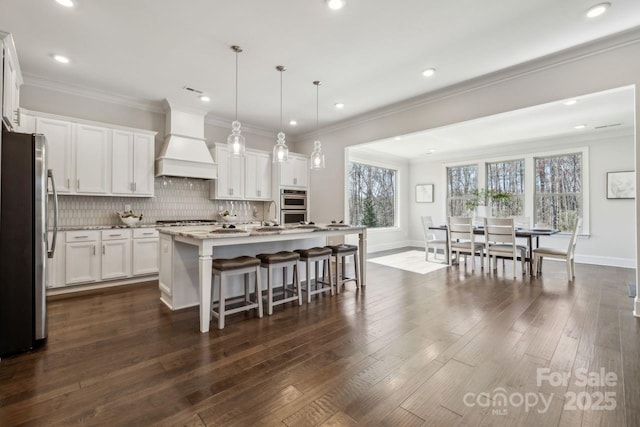 kitchen featuring premium range hood, appliances with stainless steel finishes, backsplash, dark wood finished floors, and crown molding