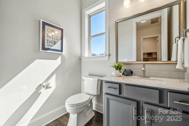 bathroom featuring visible vents, toilet, vanity, wood finished floors, and baseboards