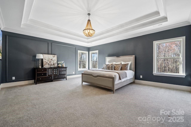 carpeted bedroom featuring visible vents, baseboards, ornamental molding, a tray ceiling, and a chandelier