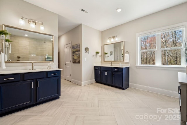 bathroom with baseboards, visible vents, a tile shower, and a sink