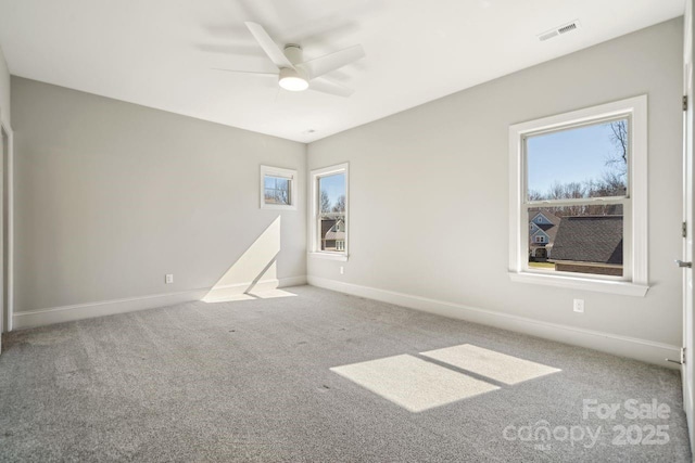 carpeted empty room featuring baseboards, visible vents, and ceiling fan