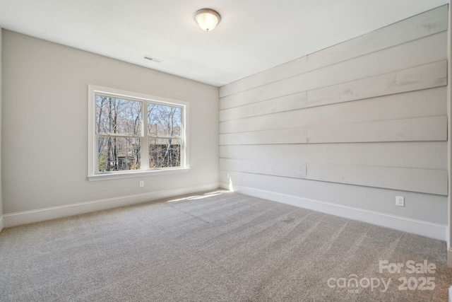 carpeted empty room featuring baseboards and visible vents