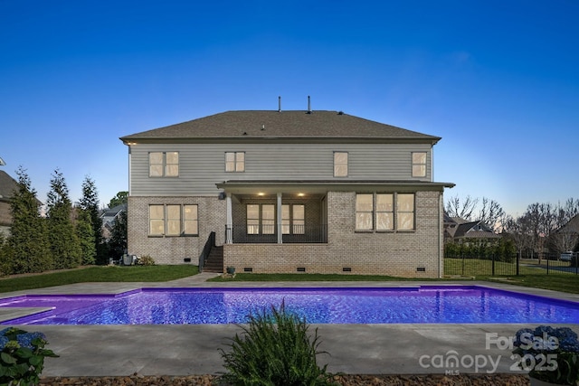 rear view of property featuring a fenced in pool, a patio area, crawl space, and brick siding