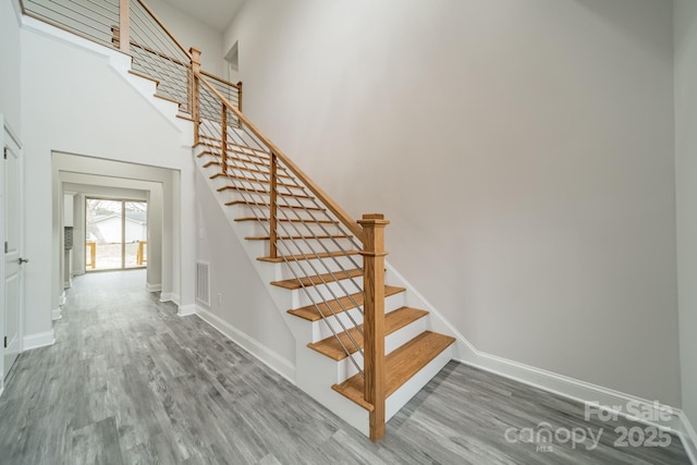 staircase with a towering ceiling and wood-type flooring