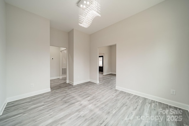 empty room featuring light hardwood / wood-style floors and a chandelier