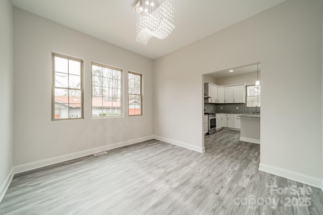 spare room with a chandelier and light hardwood / wood-style flooring