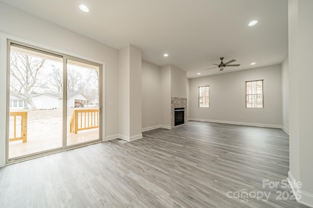 unfurnished living room featuring hardwood / wood-style flooring, ceiling fan, and a fireplace