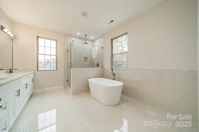 bathroom featuring independent shower and bath, vanity, and tile walls