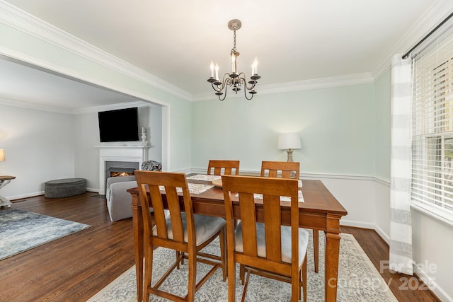 dining space with dark wood-type flooring, ornamental molding, and a chandelier