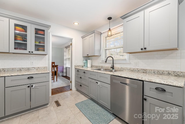 kitchen with dishwasher, sink, light stone counters, and decorative light fixtures