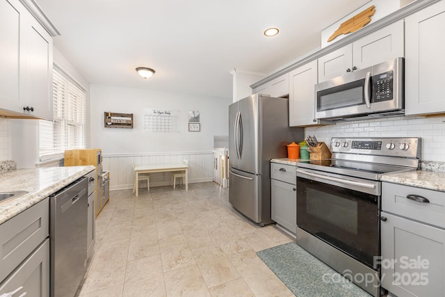 kitchen featuring tasteful backsplash, appliances with stainless steel finishes, gray cabinetry, and light stone counters