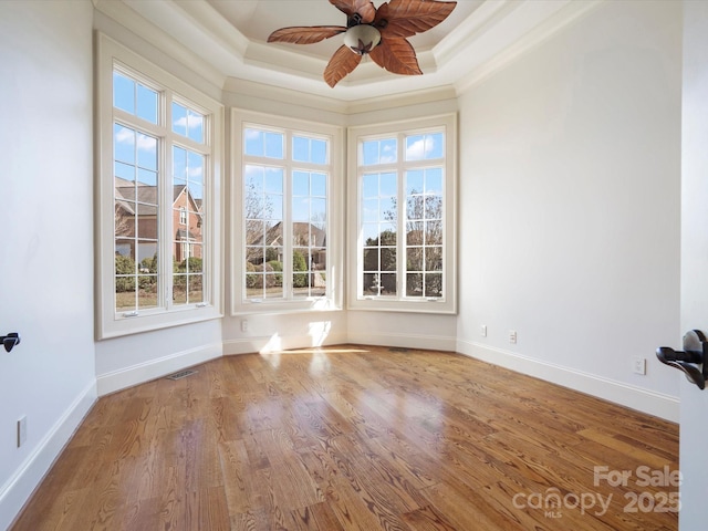 unfurnished sunroom with a ceiling fan, visible vents, and a tray ceiling