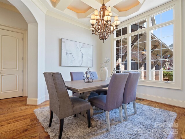 dining room featuring baseboards, arched walkways, coffered ceiling, wood finished floors, and a notable chandelier